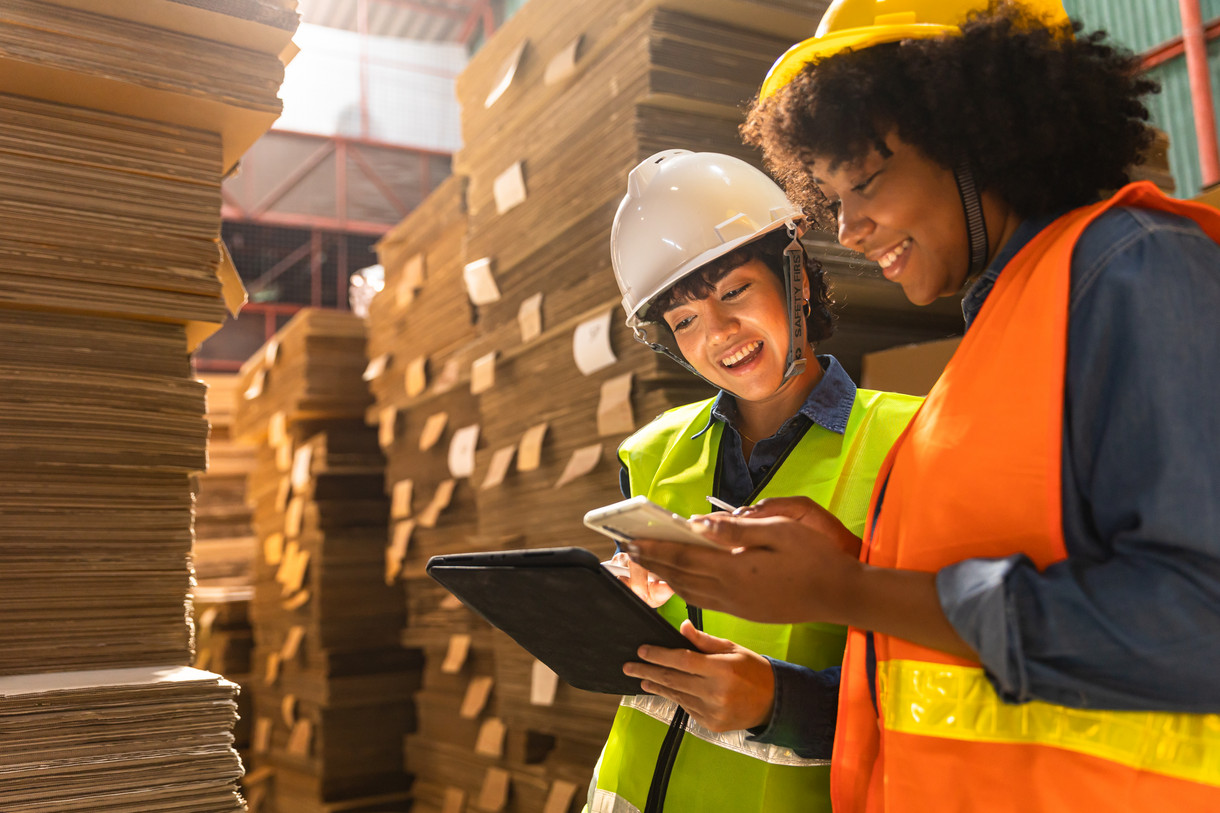 Two women in hardhats in a warehouse. Digital transformation in the logistics industry.